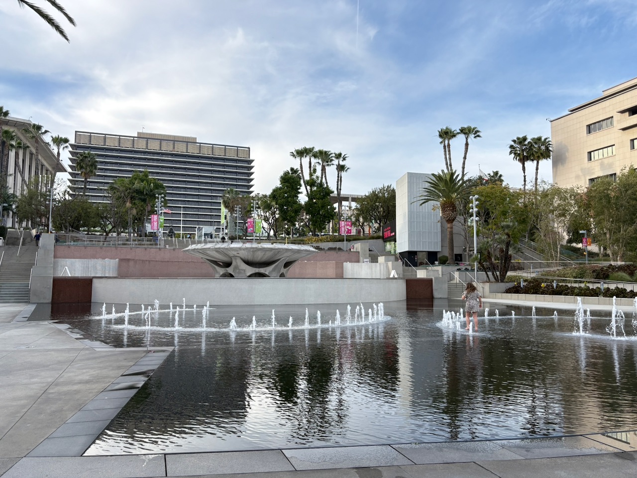 The Arthur J. Will Memorial Fountain plaza at Grand Park with water features, palm trees, and the Downtown LA skyline