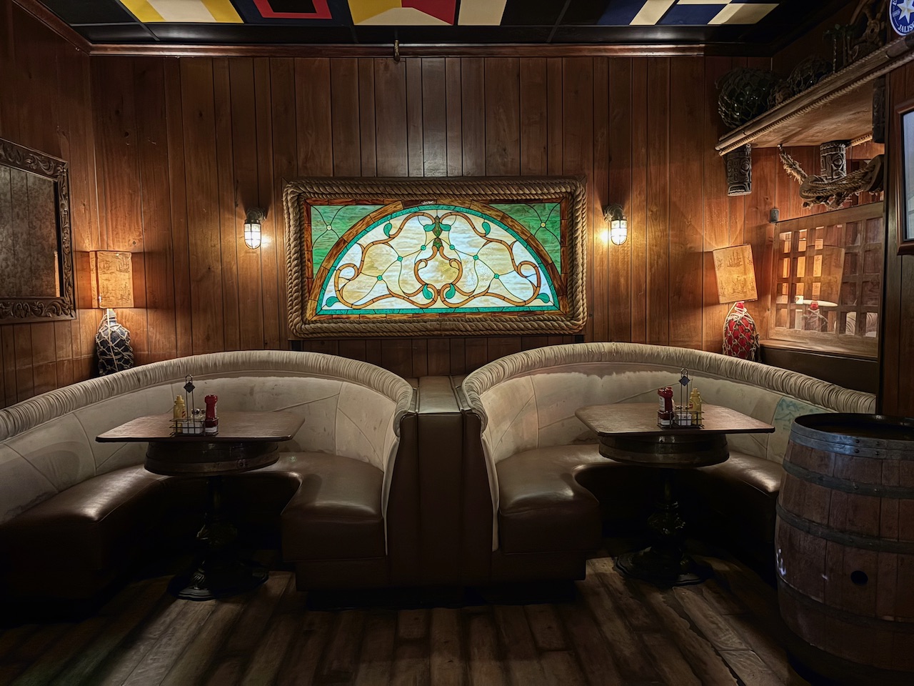 The round booth seating inside the Redwood Bar with ornate stained glass art on the wood-paneled wall